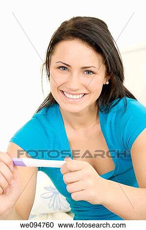 Stock Image - Young Caucasian woman holding a pregnancy test. Fotosearch