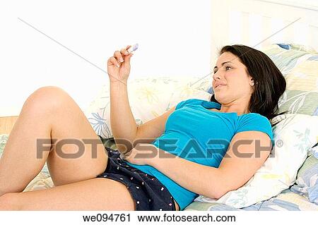Stock Image - Young Caucasian woman looking at pregnancy test. Fotosearch
