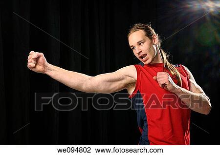 Young male with long hair practicing a swivel Karate punch while yelling in spotlight View Large Photo Image Stock Image - Young male with long hair practicing a swivel Karate punch while yelling in spotlight. Fotosearch