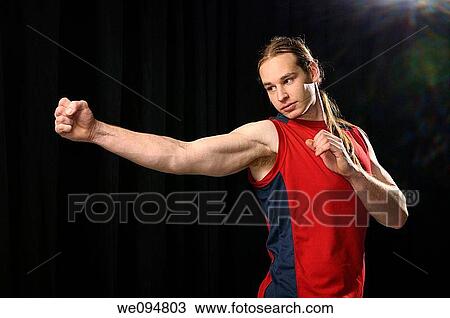 Young male with long hair showing spinning Karate punches in the spotlight View Large Photo Image Stock Image - Young male with long hair showing spinning Karate punches in the spotlight. Fotosearch
