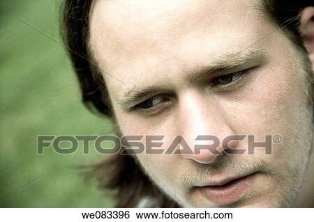 Stock Photograph - Young man posing on the grass at a park. Fotosearch