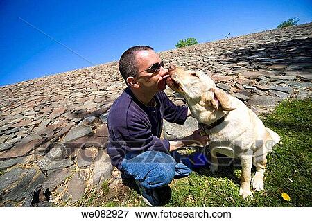 Young man, wearing sunglasses, playing with his dog View Large Photo Image Stock Photo - Young man, wearing sunglasses, playing with his dog. Fotosearch