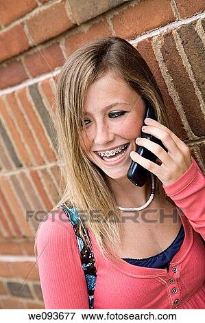 Young teenage girl talking on cell phone outside of a school building View Large Photo Image Stock Photo - Young teenage girl talking on cell phone outside of a school building. Fotosearch