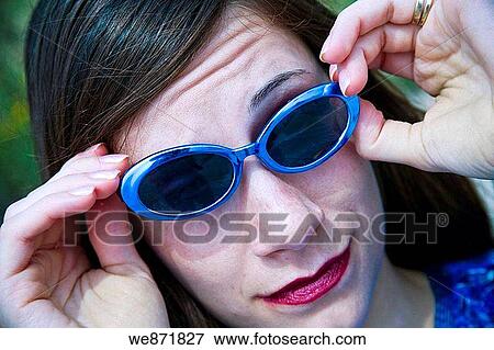 Young woman adjusting her sunglasses. View Large Photo Image Stock Photo - Young woman adjusting her sunglasses.. Fotosearch