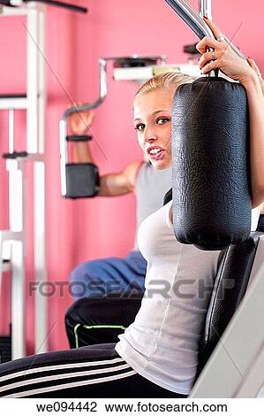 young woman doing back exercise on a machine in modern gym View Large Photo Image Stock Image - young woman doing back exercise on a machine in modern gym. Fotosearch