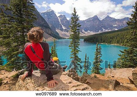 young woman from back sitting on a rock enjoying the view of moraine lake in yoho national park, canada View Large Photo Image Stock Photo - young woman from back sitting on a rock enjoying the view of moraine lake in yoho national park, canada. Fotosearch