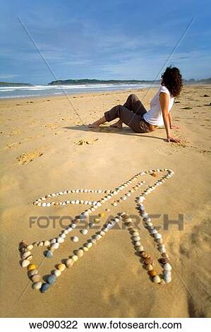 Stock Image - young woman in a beach with a plane of shells. Somo beach. Cantabria, Spain, Europe. Fotosearch