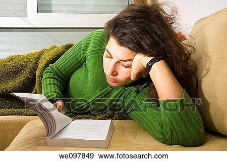 Young woman in her 20s reading a book while lying on a bed model release available Selective lighting View Large Photo Image Stock Photo - Young woman in her 20s reading a book while lying on a bed model release available Selective lighting. Fotosearch