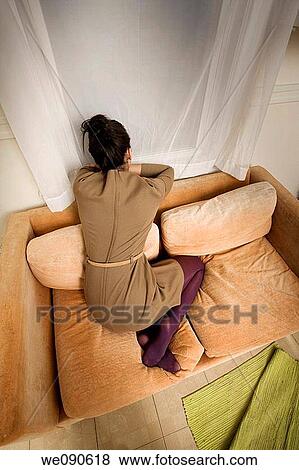 Young woman kneeling on her sofa View Large Photo Image Stock Photo - Young woman kneeling on her sofa. Fotosearch