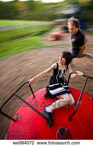 Young woman on a spinning playground ride, as her boyfriend runs alongside View Large Photo Image Stock Image - Young woman on a spinning playground ride, as her boyfriend runs alongside. Fotosearch