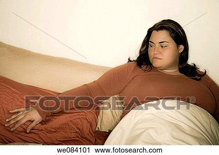 Young woman sitting on her bed. View Large Photo Image Stock Image - Young woman sitting on her bed.. Fotosearch