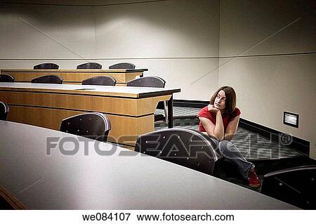 Young woman sitting on the floor in an empty college classroom View Large Photo Image Stock Photo - Young woman sitting on the floor in an empty college classroom. Fotosearch