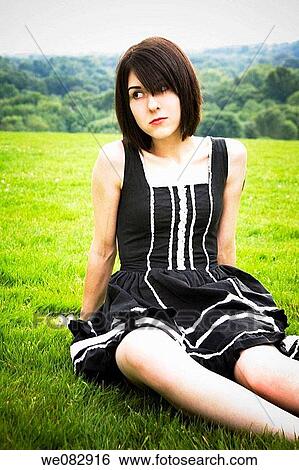Young woman sitting on the grass at a park View Large Photo Image Stock Photograph - Young woman sitting on the grass at a park. Fotosearch