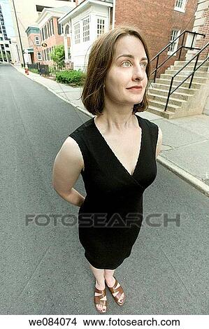 Young woman standing on a city street View Large Photo Image Picture - Young woman standing on a city street. Fotosearch