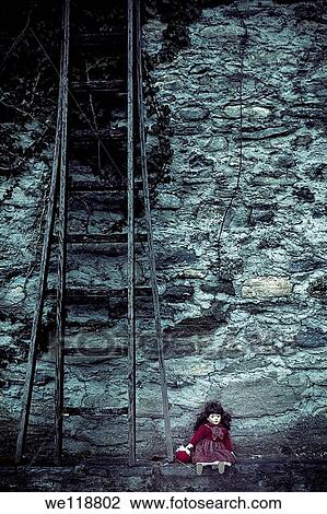 an old doll sitting on a wall next to an old wooden ladder View Large Photo Image Stock Image - an old doll sitting on a wall next to an old wooden ladder. Fotosearch