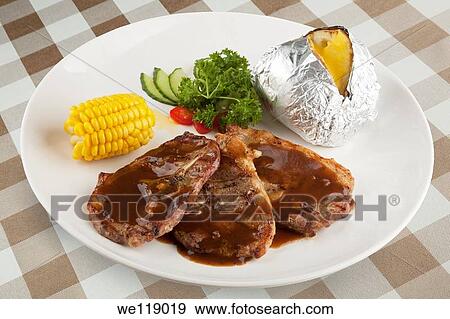 Bone in Lamb with gravy and corn and a baked potato with clipping path View Large Photo Image Stock Photo - Bone in Lamb with gravy and corn and a baked potato with clipping path. Fotosearch