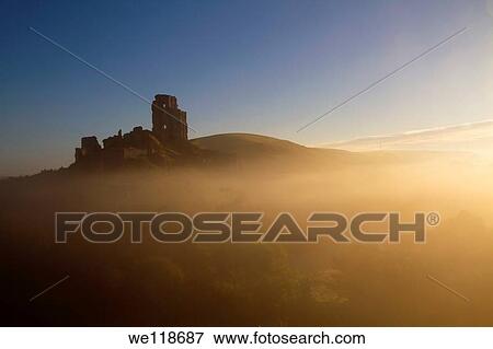 Stock Photo - Corfe Castle at dawn on a misty autumnal morning, Dorset, England, UK. Fotosearch