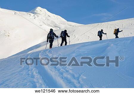 Stock Photograph - Backcountry skiers climbing slope. Fotosearch