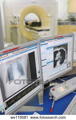 Stock Image - Female doctor and nurse monitoring MRI scan in progress. Fotosearch