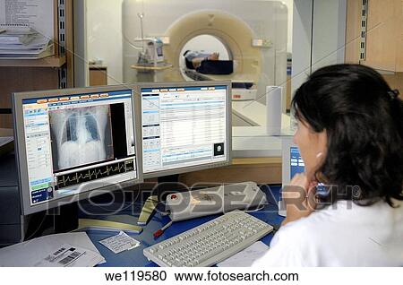 Stock Image - Female nurse monitoring MRI scan in progress. Fotosearch