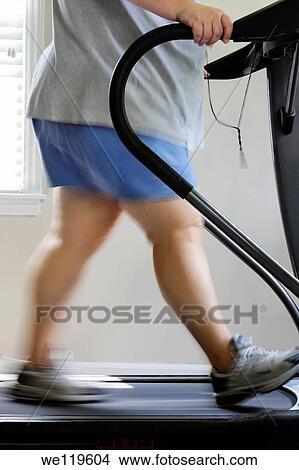 Picture - Overweight woman walking on treadmill, USA. Fotosearch