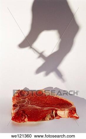 Stock Image - Shadow of hand and syringe above T-bone steak. Fotosearch