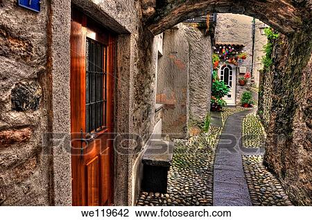 Stock Image - Tight alley with old rustic houses. Fotosearch