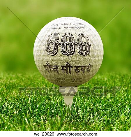 Stock Photograph - Close-up view of golf ball covered with Indian five hundred Rupee note. Fotosearch