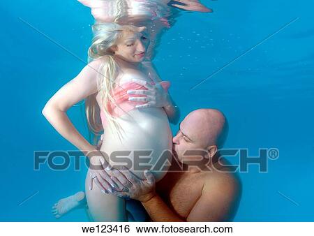 Stock Photograph - pregnant woman & man, underwater fashion in a pool. Fotosearch