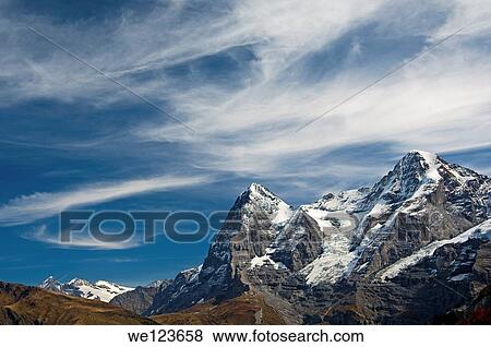 The mountain range of the Bernese Alps with the Eiger summit under a dramatic sky with cirrus clouds, Bernese Oberland, Switzerland View Large Photo Image Stock Photo - The mountain range of the Bernese Alps with the Eiger summit under a dramatic sky with cirrus clouds, Bernese Oberland, Switzerland. Fotosearch