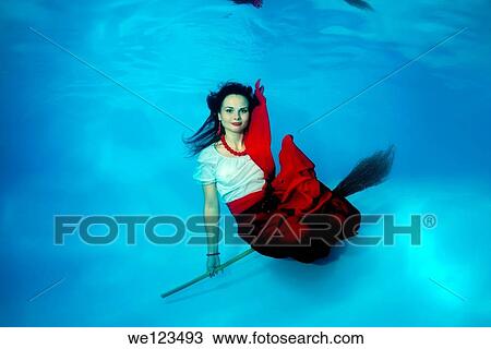 Stock Image - Woman presenting underwater fashion in a pool. Fotosearch