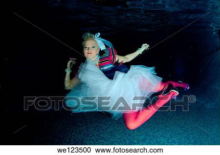 Stock Image - Woman, underwater model presenting fashion in pool. Fotosearch