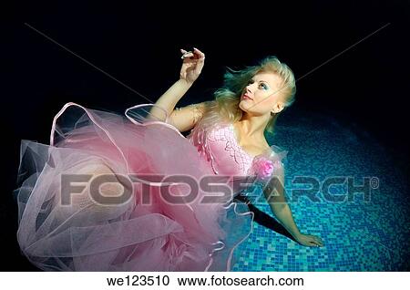 Stock Image - Woman, underwater model presenting fashion in pool. Fotosearch