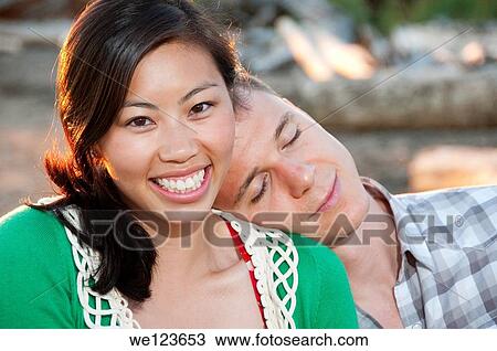 Stock Image - Young boy has his head on a chinese girls shoulder. She has a large smile.. Fotosearch