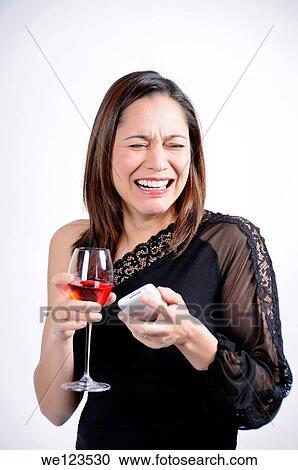 Stock Image - Young woman crying and has a glass of wine in her hand along with a telephone She is of mixed ethnicity. Fotosearch
