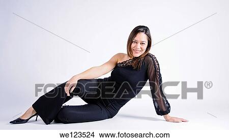 Young woman of filipino ethnicity sitting sideways on a white background She has her arm on her leg View Large Photo Image Picture - Young woman of filipino ethnicity sitting sideways on a white background She has her arm on her leg. Fotosearch