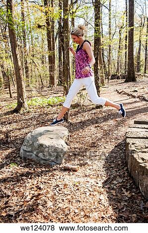 A 22 year old blond woman wearing casual clothes jumping on rocks in a garden setting. View Large Photo Image Stock Photo - A 22 year old blond woman wearing casual clothes jumping on rocks in a garden setting.. Fotosearch