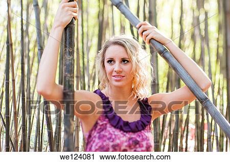 A happy 22 year old blond woman wearing casual clothes walking among bamboo canes in a garden. View Large Photo Image Stock Image - A happy 22 year old blond woman wearing casual clothes walking among bamboo canes in a garden.. Fotosearch