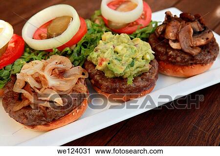 Stock Image - Three mini hamburgers with onions, guacamole and mushrooms.. Fotosearch