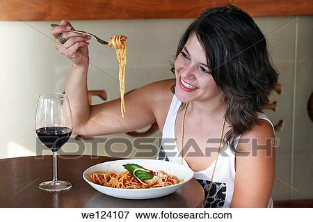 Stock Photo - Young woman eats spaghetti. Fotosearch