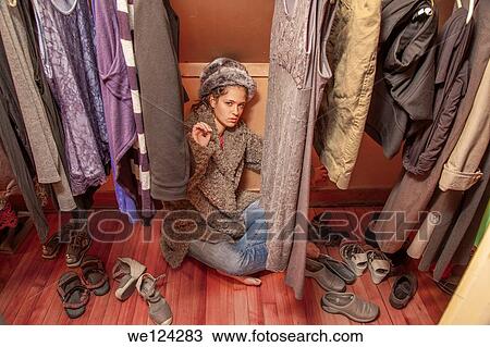 Stock Image - Teen girl in her mother's clothes closet.. Fotosearch