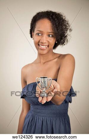 Young black woman holding a very small trophy cup. View Large Photo Image Stock Photograph - Young black woman holding a very small trophy cup.. Fotosearch