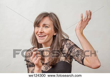 Stock Image - Young woman with a pregnancy tester.. Fotosearch