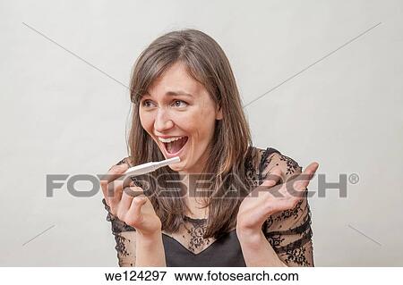 Stock Photo - Young woman with a pregnancy tester.. Fotosearch