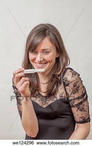 Stock Photograph - Young woman with a pregnancy tester.. Fotosearch