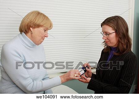 Stock Image - Aromatherapist shows medical treatment to patient. Fotosearch