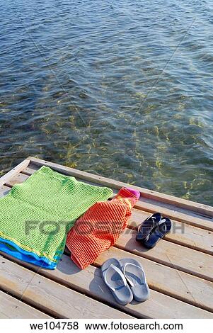 Beach towels and sandals on a wooden patio by the sea in Sicily Italy View Large Photo Image Stock Photo - Beach towels and sandals on a wooden patio by the sea in Sicily Italy. Fotosearch
