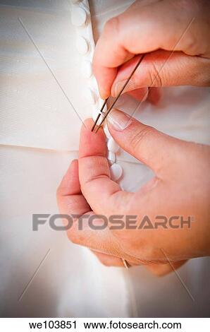 Stock Image - Hands buttoning up the bride's wedding dress. Fotosearch