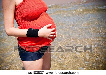 Pregnant woman standing in the sea by the beach View Large Photo Image Stock Photo - Pregnant woman standing in the sea by the beach. Fotosearch