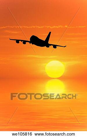 Stock Photograph - Airliner flying into the sunset over the ocean. Fotosearch